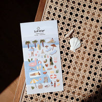 Sheet of stickers with beach-themed designs on a textured surface