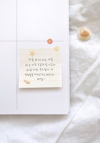Notebook with handwritten text on a white surface with seashells