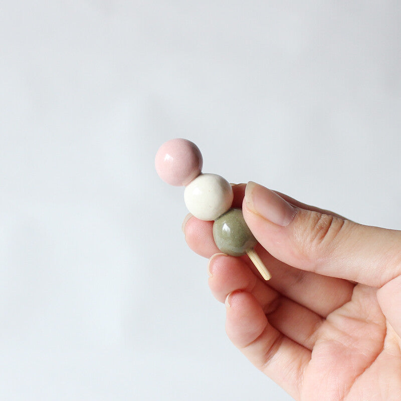 Sanshoku dango ceramic chopstick rest held in a hand