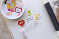 Stickers on a magazine page with a small dish containing more stickers.